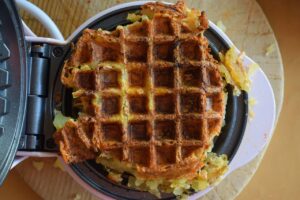 A cooked waffle iron smashed potato on the waffle maker.