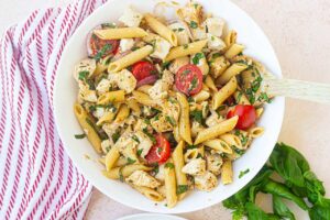 Overhead view of a white bowl filled with chicken pasta salad.