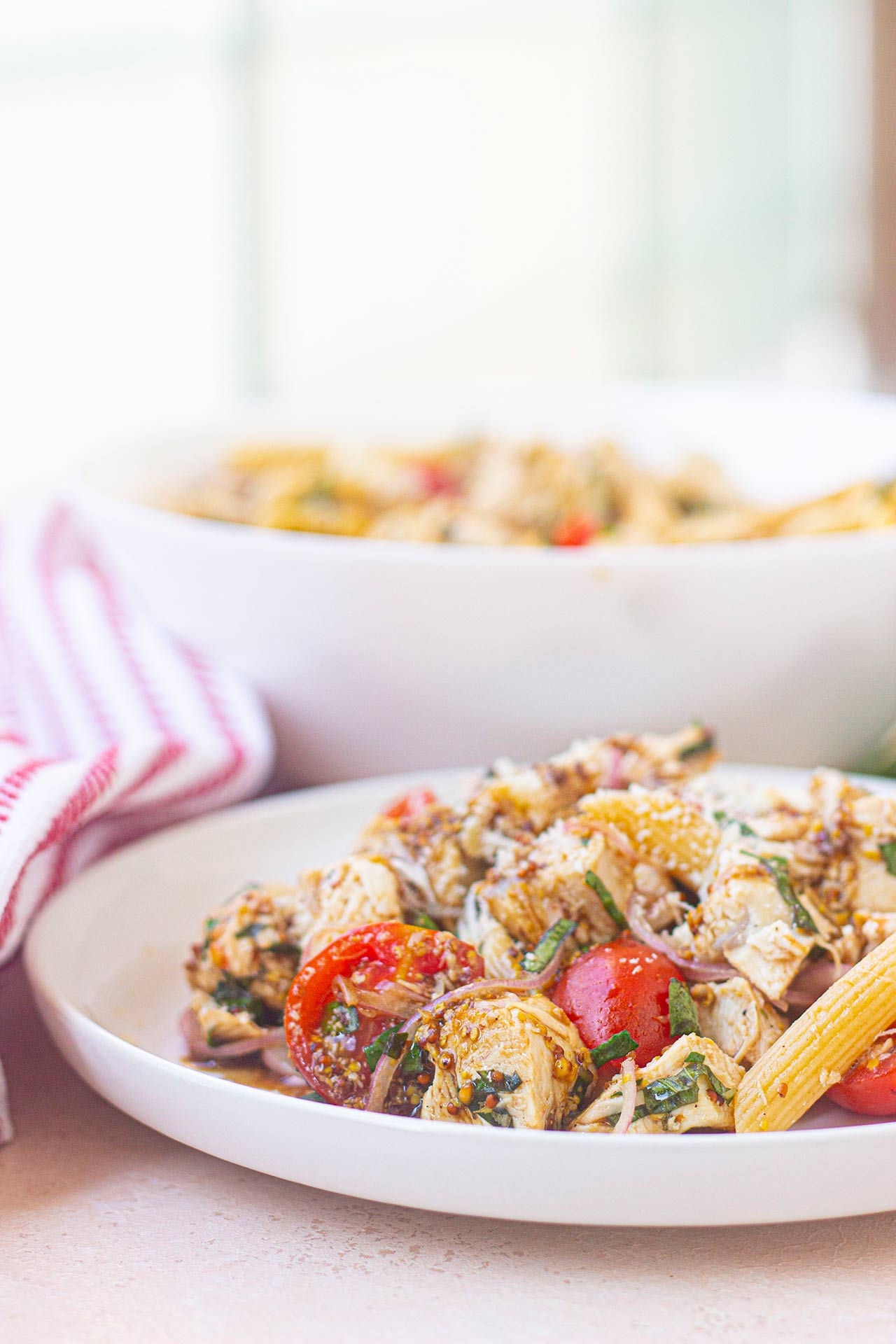 Closeup front view of a white plate with chicken pasta salad on it.