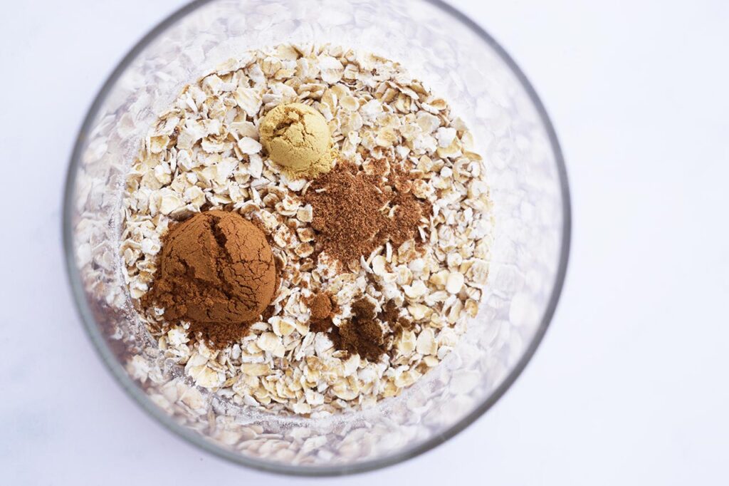 Spices added to a glass jar of oats.