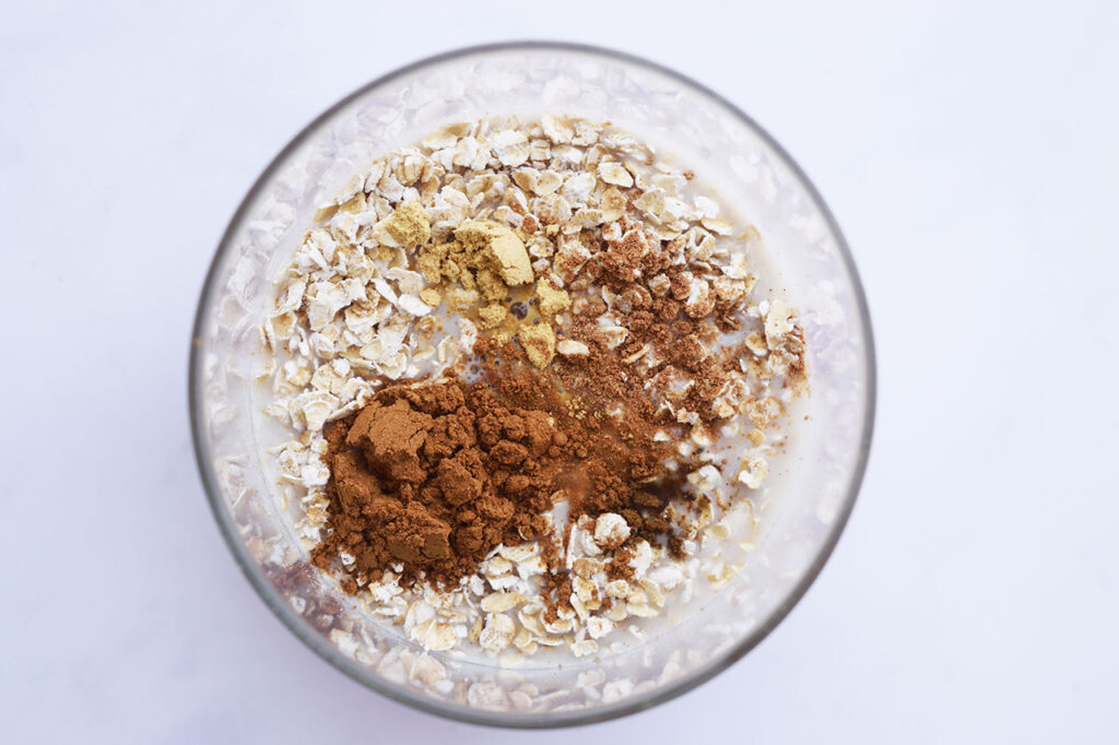 Milk added to a glass jar with oats and spices.