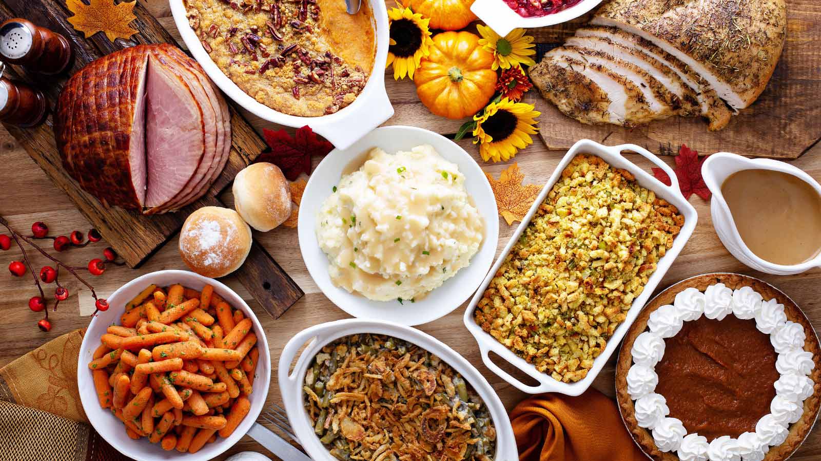 Thanksgiving table with roasted turkey, sliced ham and side dishes