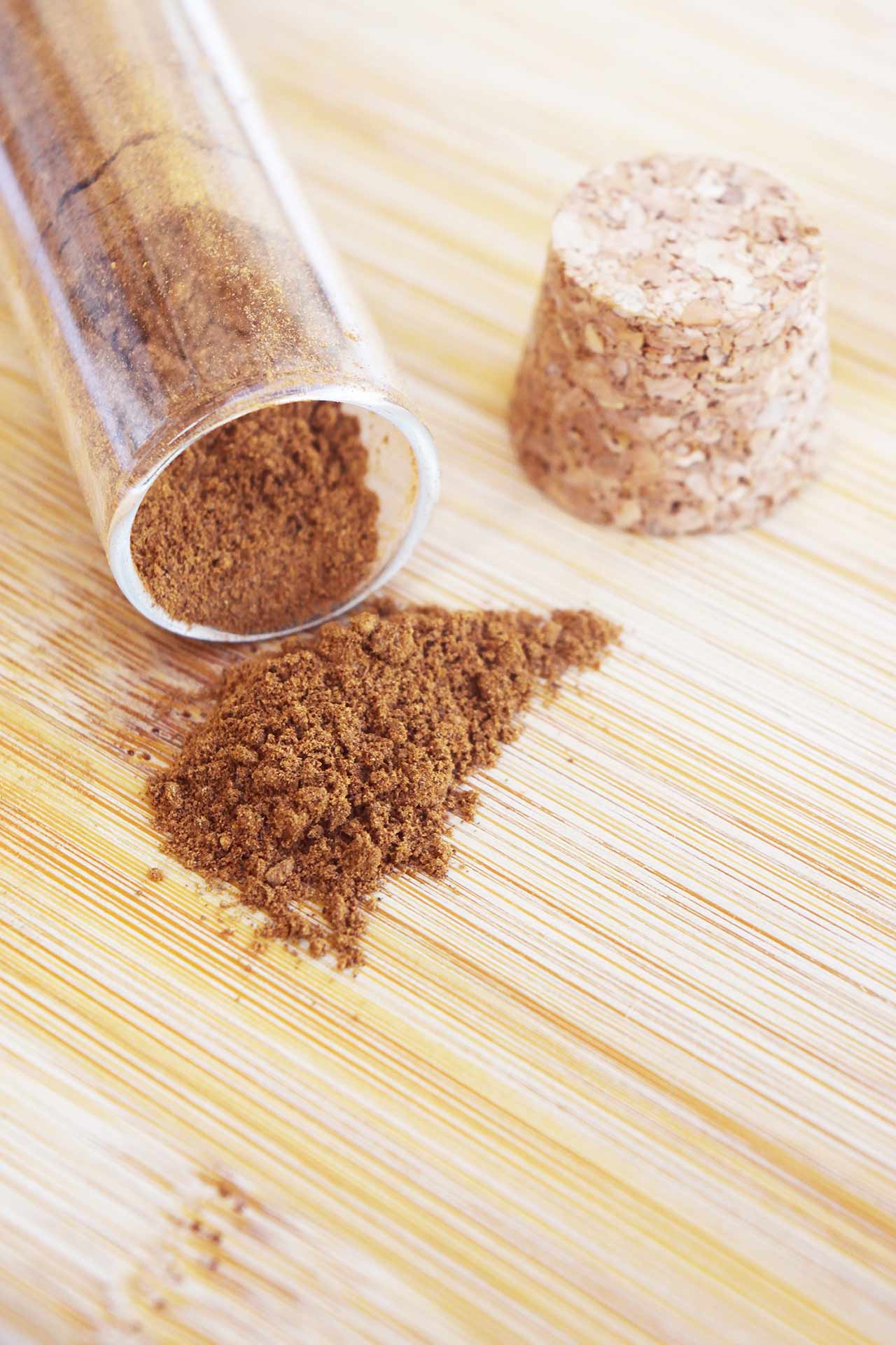 Side view of a tipped over jar of mulling spices on a wood surface.