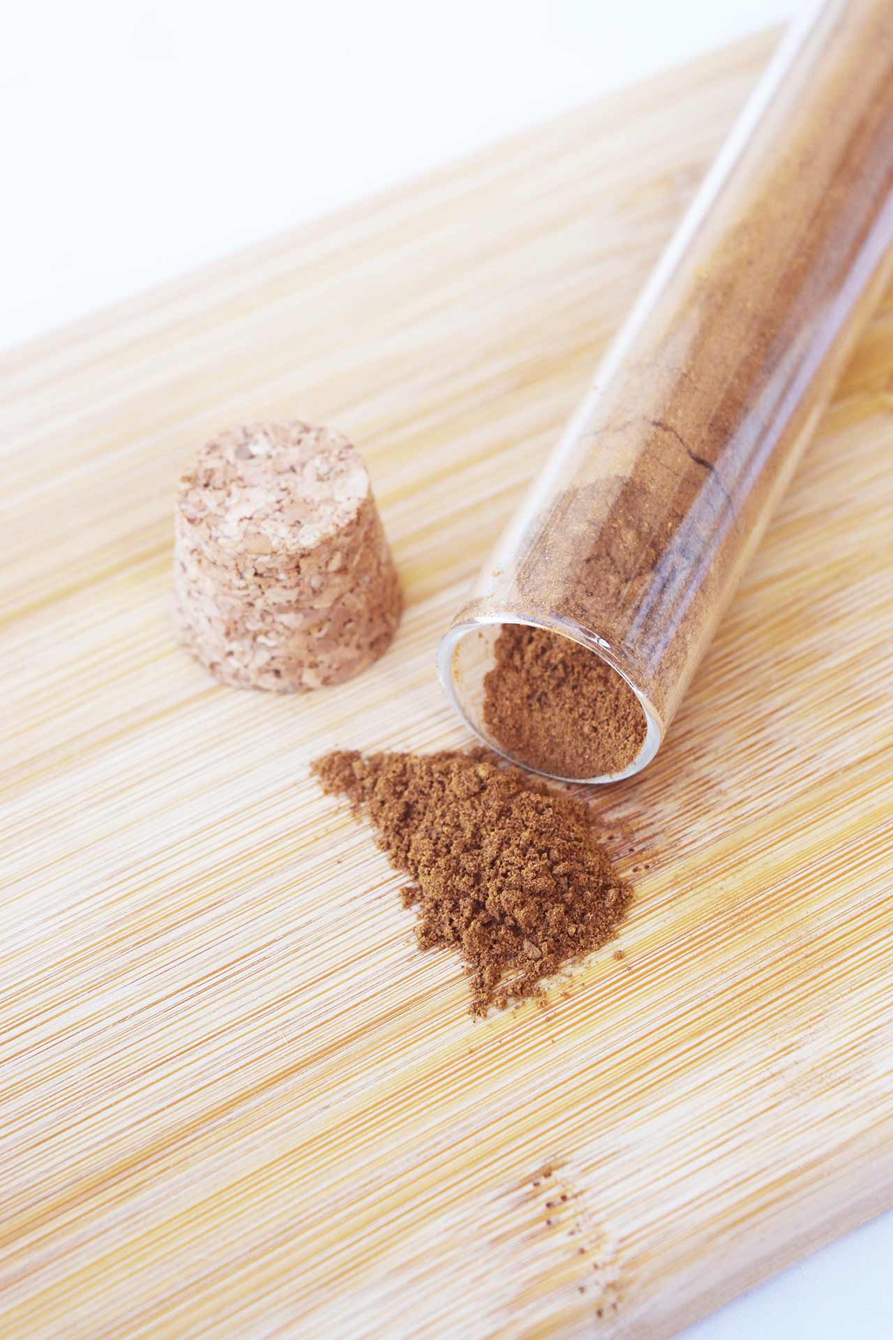 Overhead view of a tipped over jar of mulling spices on a wood surface.