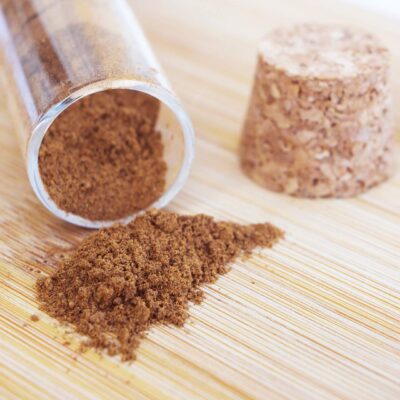Closeup of tipped over spice jar on a wood surface with mulling spices falling out.