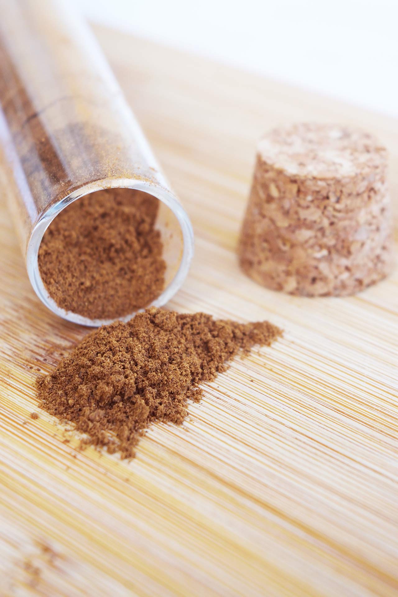 Closeup of tipped over spice jar on a wood surface with mulling spices falling out.