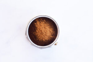 Cinnamon sprinkled over coffee in the Moka pot coffee basket.