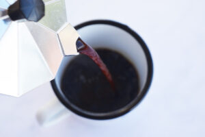 Pouring coffee from a Moka pot into a mug.