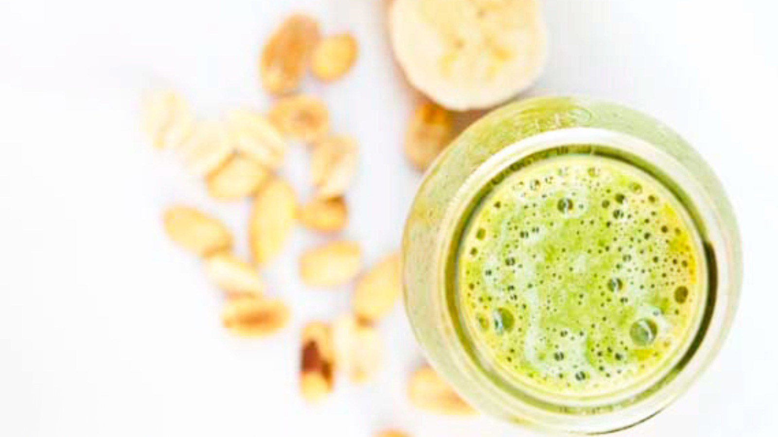 Overhead view of a glass of Peanut Butter And Banana Smoothie on a white background.