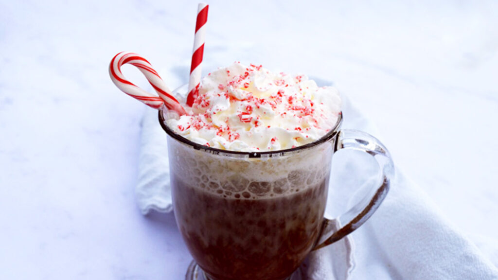 A just-made peppermint latte topped with whipped cream and crushed candy cane.