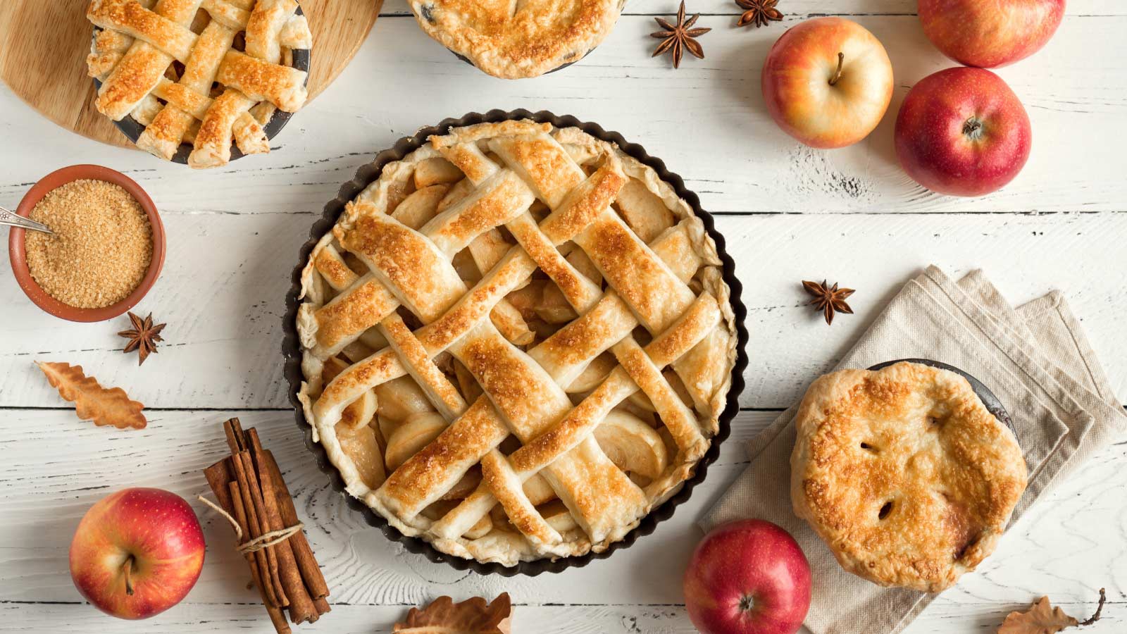 Homemade Apple Pies on white wooden background, top view. Classic autumn Thanksgiving dessert - organic apple pie.