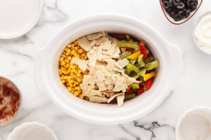 Torn bits of tortillas added to a slow cooker crock.