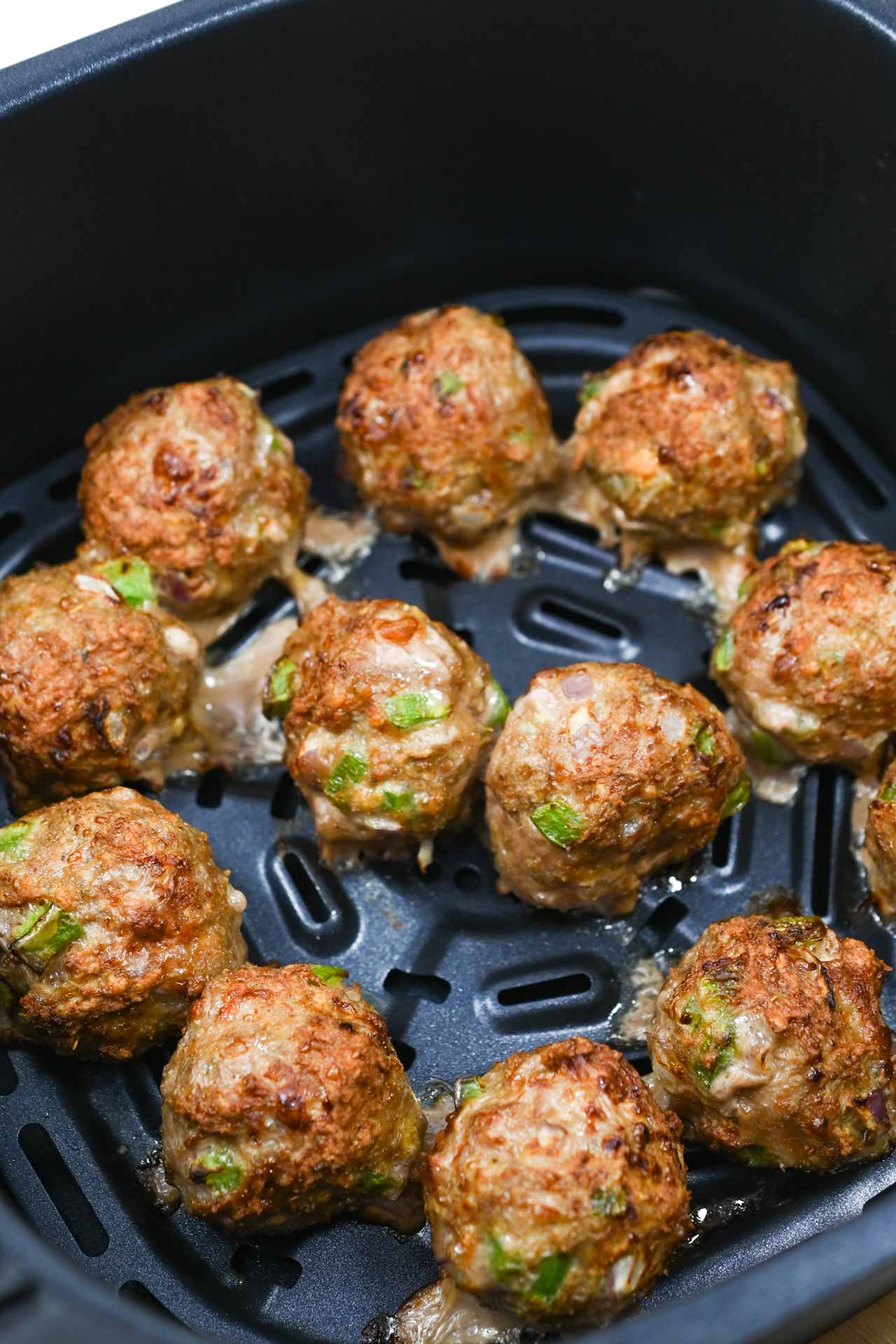 Cooked Air Fryer Meatballs sitting in an air fryer basket.