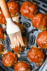 Basting the meatballs with ketchup.