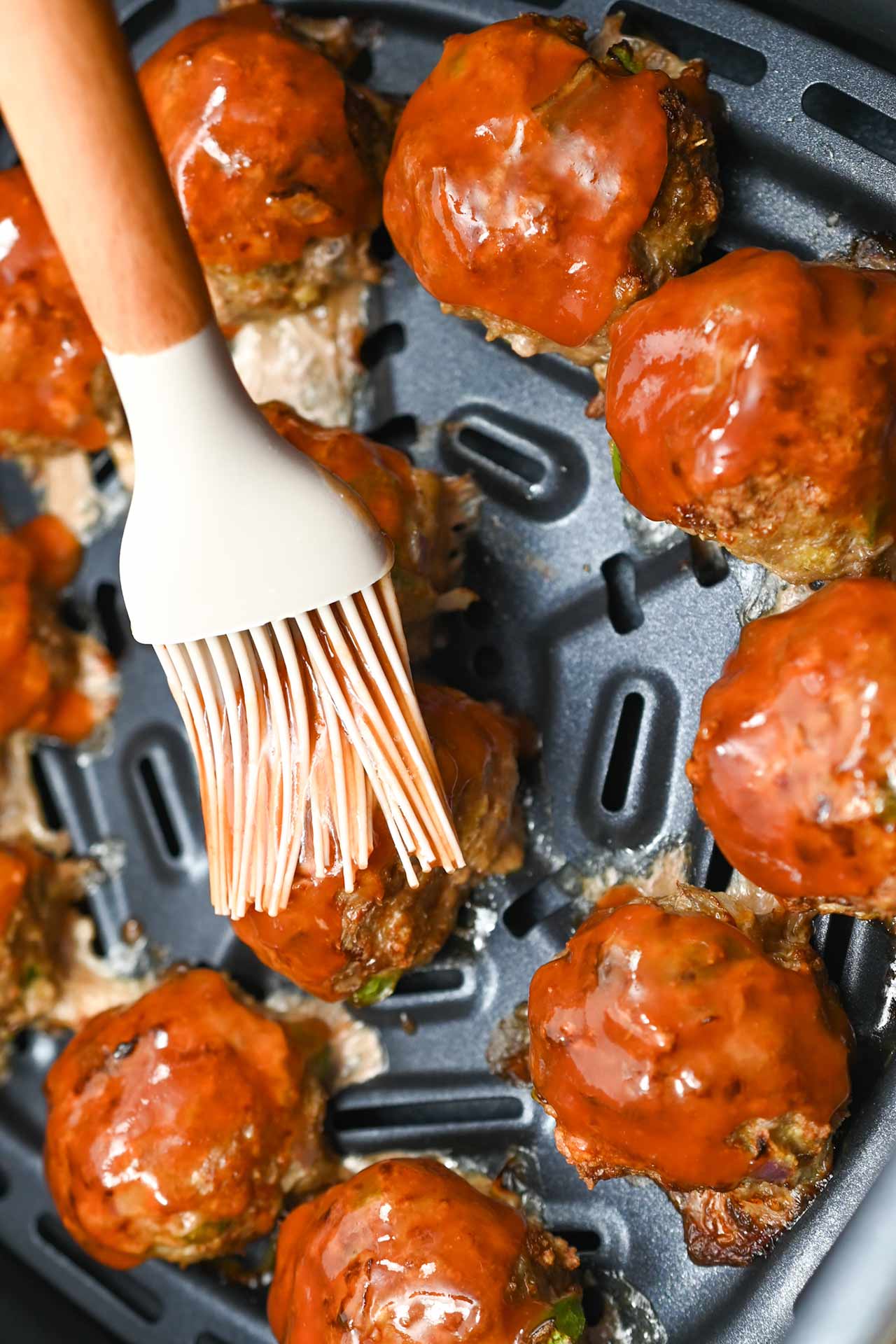 Basting the meatballs with ketchup.