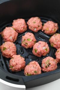 Formed meatballs in an air fryer basket.
