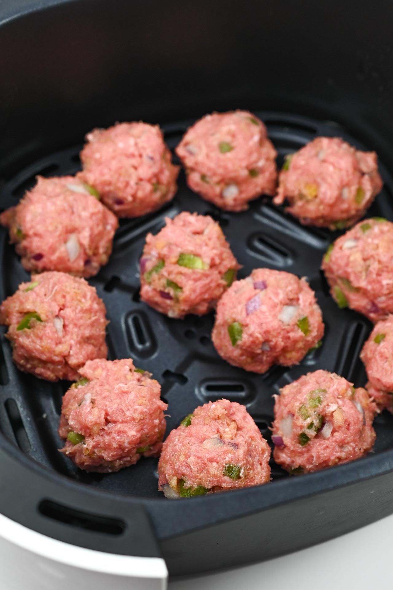 Formed meatballs in an air fryer basket.