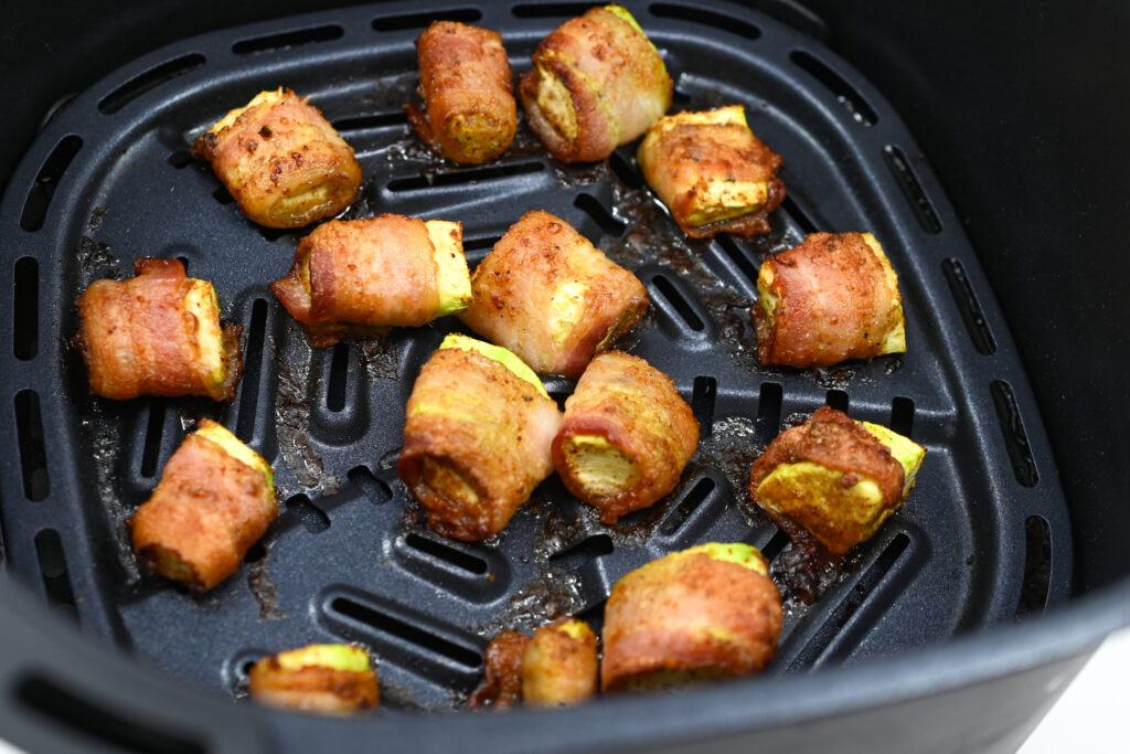Cooked Bacon-Wrapped Zucchini in an air fryer basket.