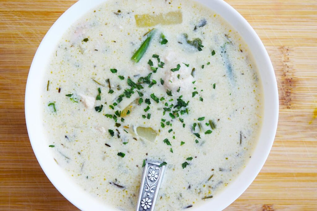 Closeup of a white bowl filled with Chicken Pot Pie Soup. Overhead view.