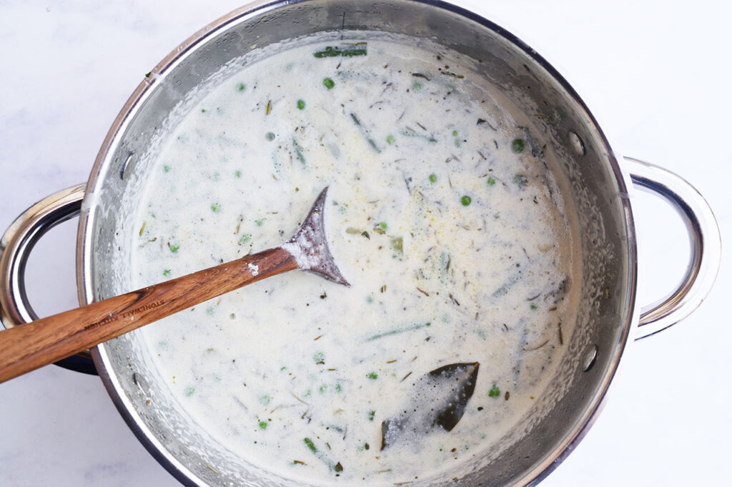 Cream added to the Chicken Pot Pie Soup in a soup pot.