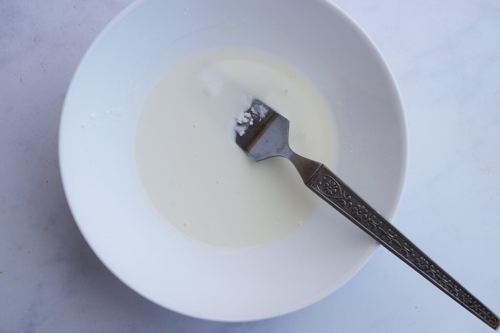 Water whisked together with cornstarch in a bowl. A fork rests in the bowl.