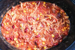 Chicken shredded in a slow cooker crock full of Chicken Taco Chili.