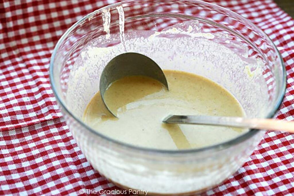 Pancake batter in a mixing bowl with a ladle.