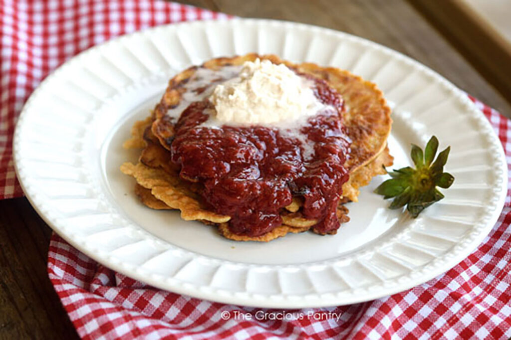 Chunky Strawberry Pancake Syrup on a short stack of pancakes topped with whipped cream.