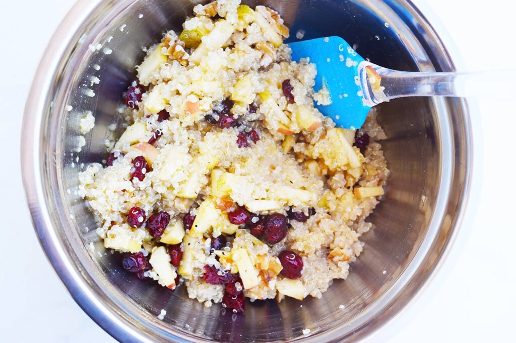 Cranberry Apple Quinoa Salad mixed with dressing in a mixing bowl.