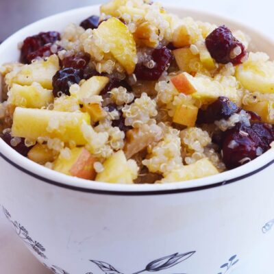 Front view of a decorative mug filled with Cranberry Apple Quinoa Salad.