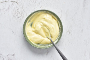 Overhead view of a bowl of mayo with a spoon.