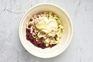 Mayo and spices added to Cranberry Chicken Salad ingredients in a mixing bowl.