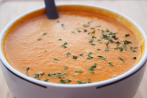 Closeup of a white mug filled with creamy tomato soup.