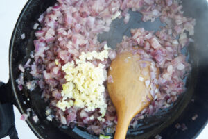 Minced garlic added to sautéed onions in a skillet.