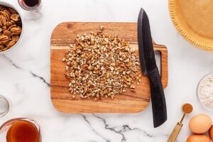 Chopped pecans on a wood cutting board.