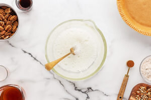 Whipped egg whites in a glass bowl with a fork.