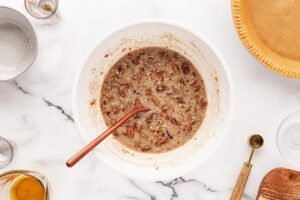 Mixed pecan pie filling in a white mixing bowl.