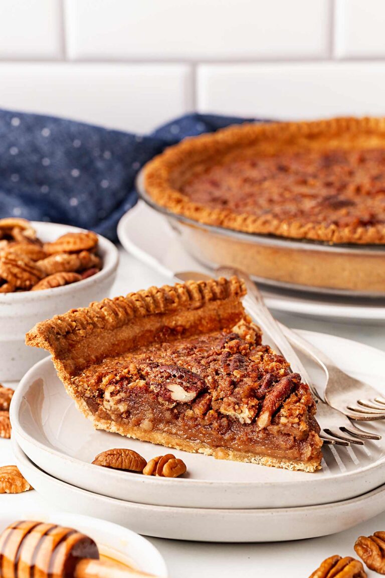A single slice of pecan pie on a white plate with forks.
