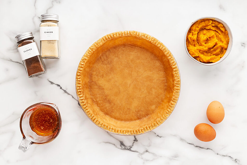 Pumpkin Pie ingredients on a white marble surface.