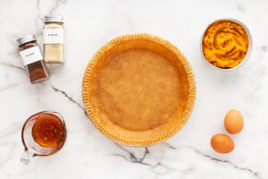 Pumpkin Pie ingredients on a white marble surface.