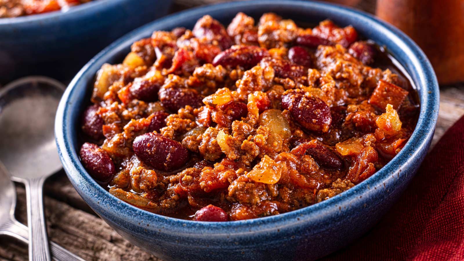 A bowl of delicious spicy hot chili con carne with ground beef, onion, tomato and red kidney beans.