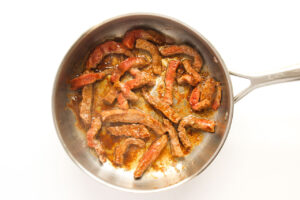 Seasoned steak strips browned in a skillet.