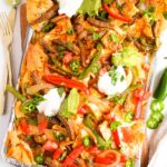 Steak Nachos with all the toppings on a sheet pan.