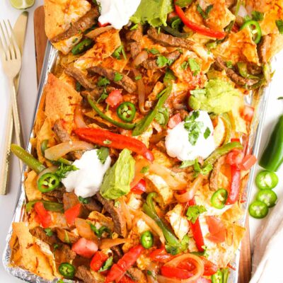 Steak Nachos with all the toppings on a sheet pan.