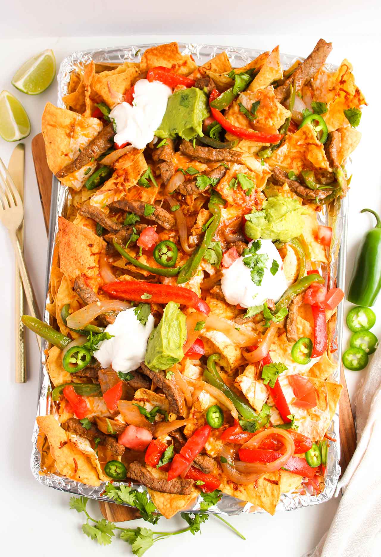 Overhead view. A sheet pan full of Steak Nachos with toppings.