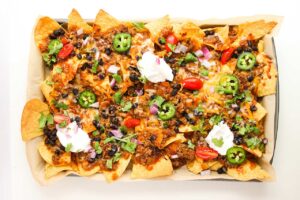 Sour cream, tomatoes, and fresh jalapeno slices added to Beef Enchilada Nachos for garnish.