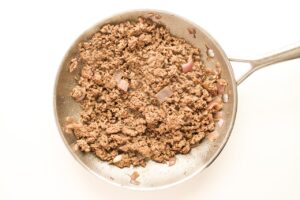 Cooked ground beef with onions in a skillet.