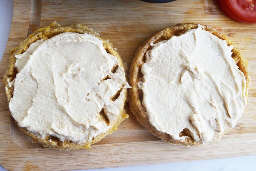 Two pieces of bread with hummus spread over them.