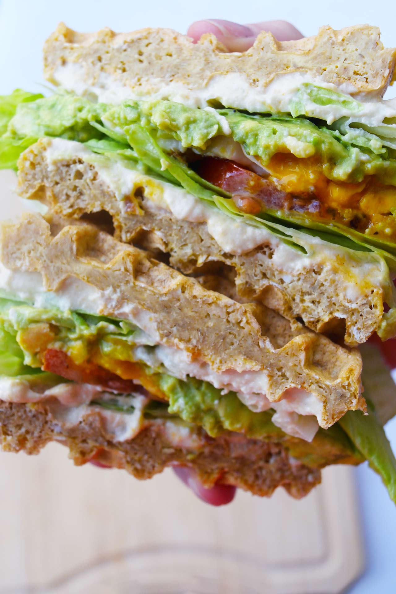 A hand holds a stacked Breakfast Mediterranean Sandwich that's been cut in half.