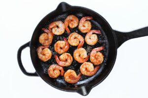 Cooked, seasoned shrimp in a black skillet.